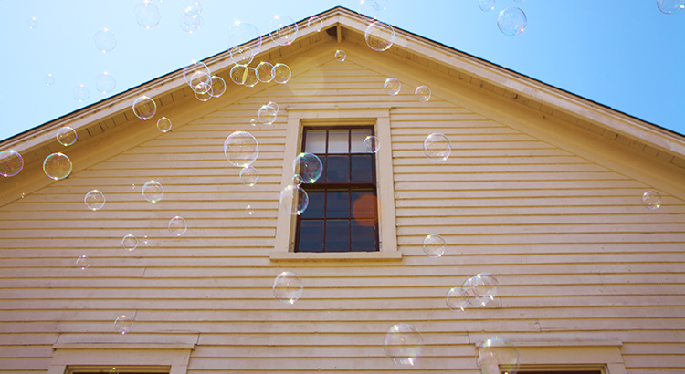soap bubbles floating in front of yellow house